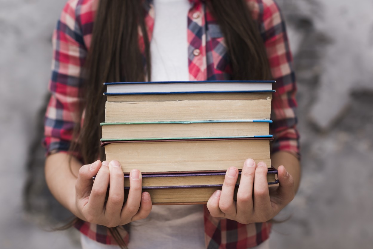 Fille tenant une pile de livres